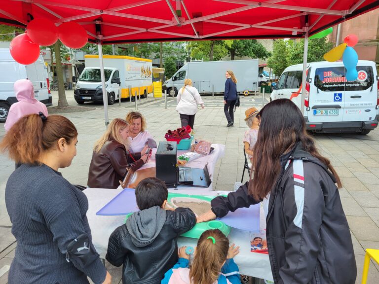 Familien bei einer Mitmachaktion zur Betreuung und Pflege am Lernmobil-Stand